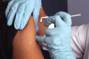 A vaccine mandate at a workplace in North America results in a worker receiving a COVID-19 vaccination.